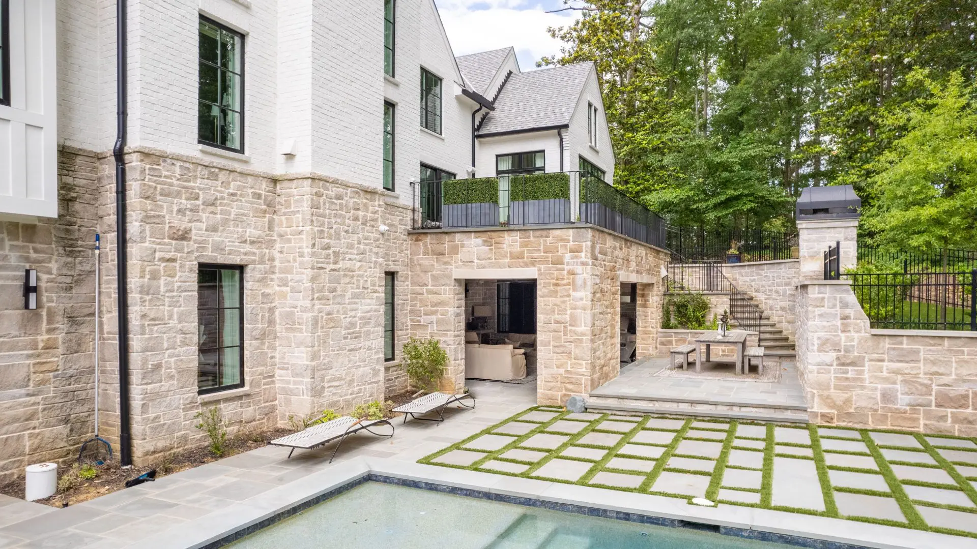 A large pool and patio area with a stone wall.