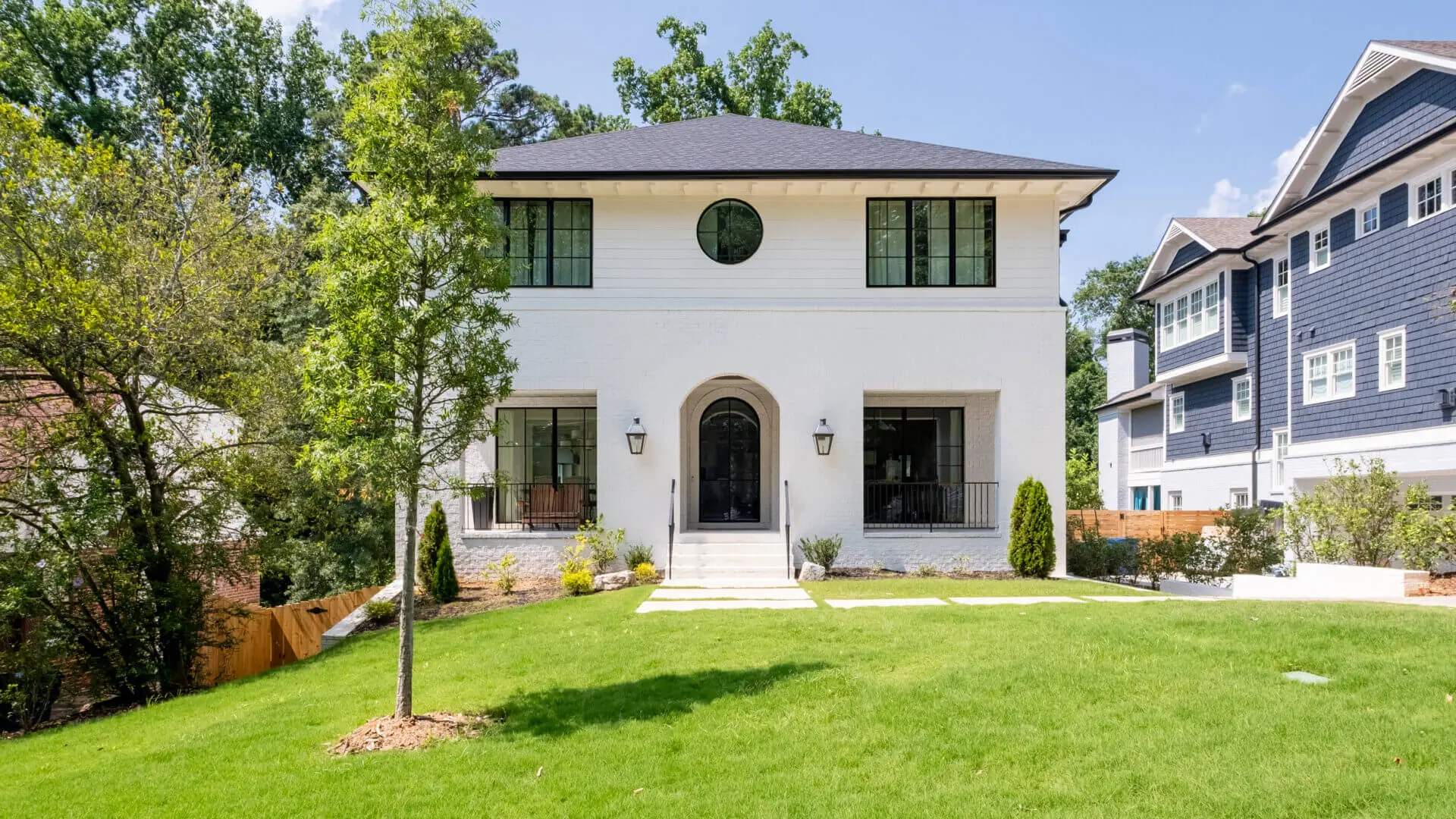 A white house with black windows and a green roof.